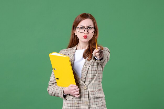 Portrait of female teacher with yellow files on green