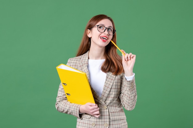 Portrait of female teacher with yellow files on green