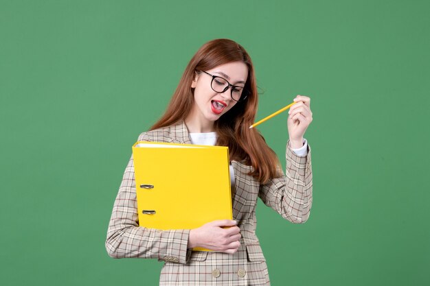 Portrait of female teacher with yellow files on green