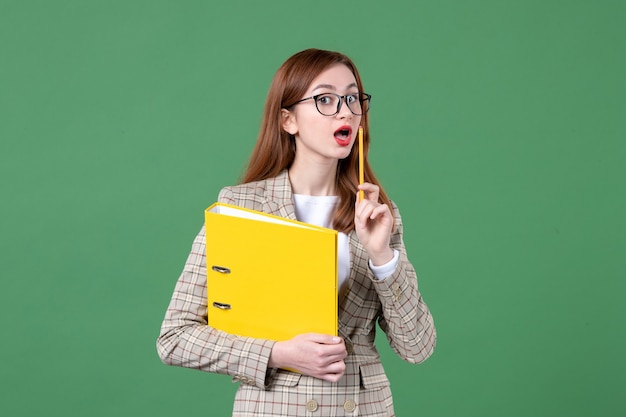 Portrait of female teacher with yellow files on green