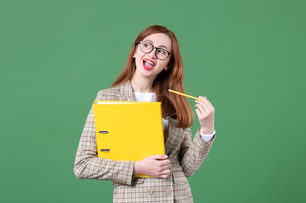 Portrait of female teacher with yellow files on green