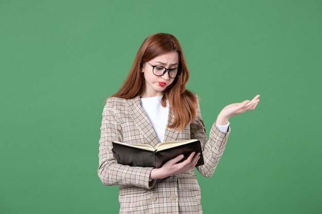 Portrait of female teacher writing down notes on green