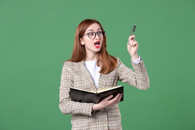 Portrait of female teacher writing down notes on green