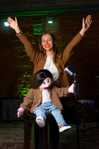 Foto gratuita ritratto di ventriloquo femminile durante lo spettacolo con burattino