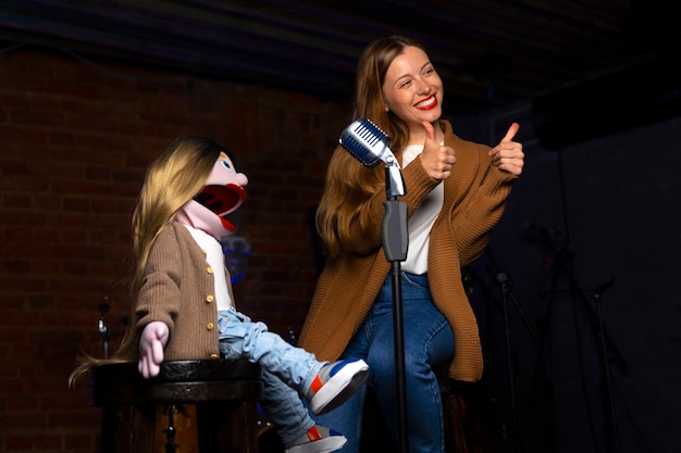 Foto gratuita ritratto di ventriloquo femminile durante lo spettacolo con burattino