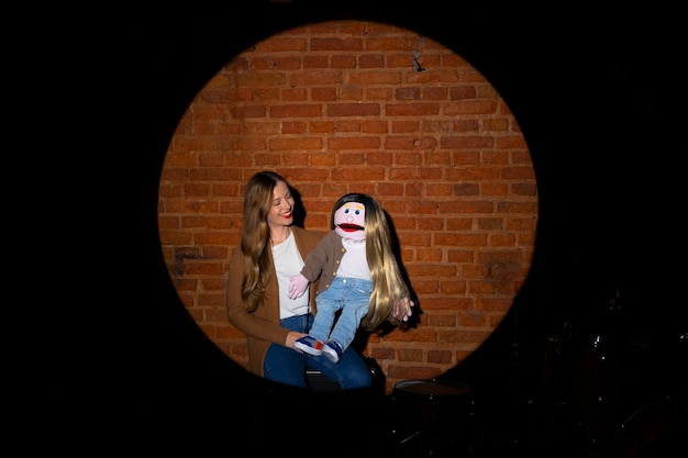 Portrait of female ventriloquist with puppet at show