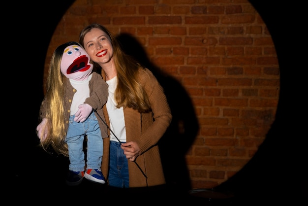 Foto gratuita ritratto di donna ventriloquo con burattino in mostra