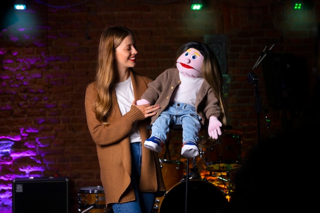 Foto gratuita ritratto di donna ventriloquo con burattino in mostra