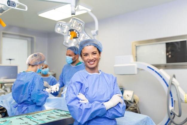 Portrait of female woman nurse surgeon OR staff member dressed in surgical scrubs gown mask and hair net in hospital operating room theater making eye contact smiling pleased happy looking at camera