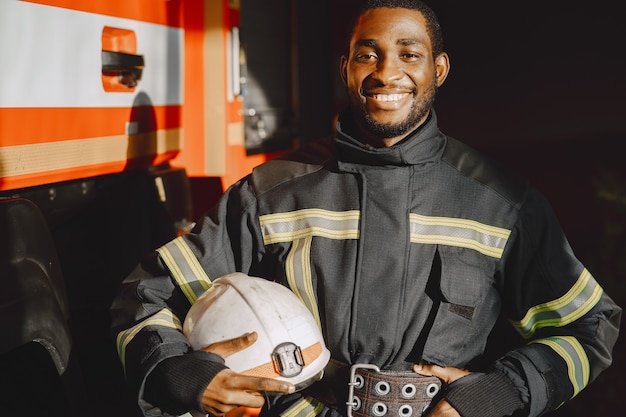 Портрет пожарного, стоящего перед пожарной машиной