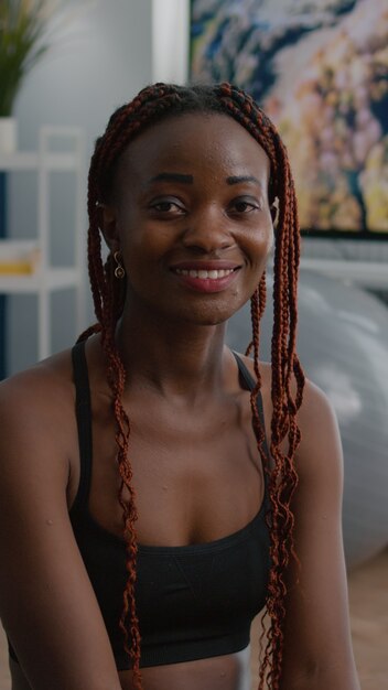 Portrait of fit black woman looking into camera while sitting in lotus position