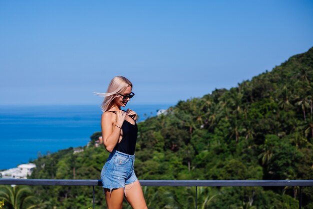 Portrait of fit european woman in swimsuit and denim shorts on vacation