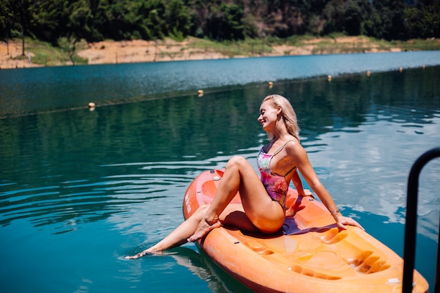 Портрет подходящей молодой кавказской туристической женщины в бикини, расслабляющемся на байдарке на красивом озере в Таиланде. Женщина в отпуске, наслаждаясь солнечным днем.