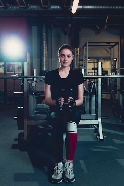 Foto gratuita ritratto di una giovane donna adatta che si esercita con i dumbbells in ginnastica