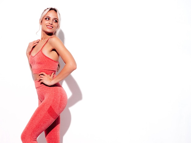 Free photo portrait of fitness smiling woman in pink sports clothing sexy young beautiful model with perfect bodyfemale isolated on white wall in studiocheerful and happy stretching out before training