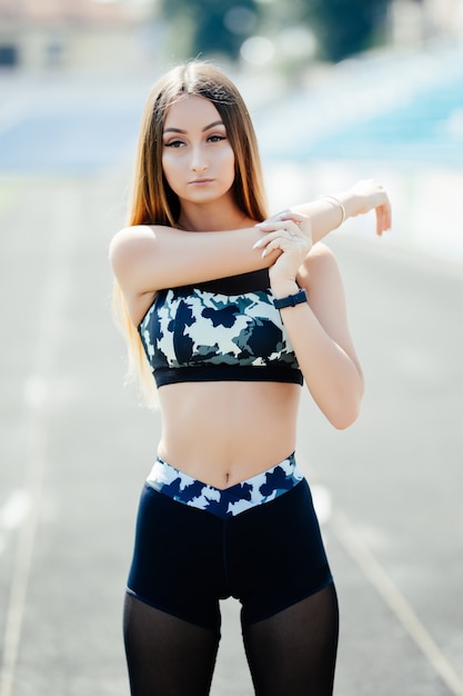 Free photo portrait of a fitness woman doing warm up exercises outdoors