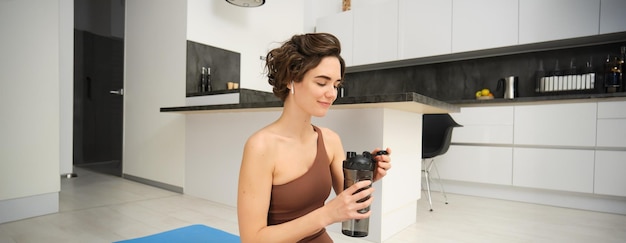 Free photo portrait of fitness woman young sportswoman at home drinks water from bottle after workout training