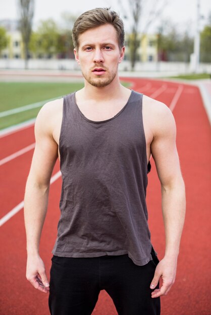 Portrait of fitness young man standing on track field