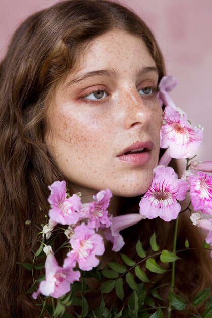 彼女の顔にピンクの花を持っているそばかすのある女性の肖像画