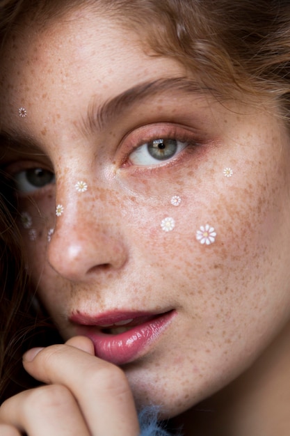 Portrait of freckled woman with white flowers on her face