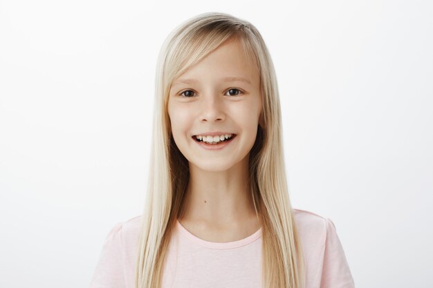 Portrait of friendly carefree adorable kid with blond hair, smiling broadly and expressing positive attitude, enjoying great day spending in drama classes