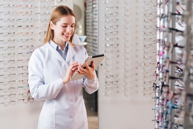 Portrait of friendly female optometrist using tablet