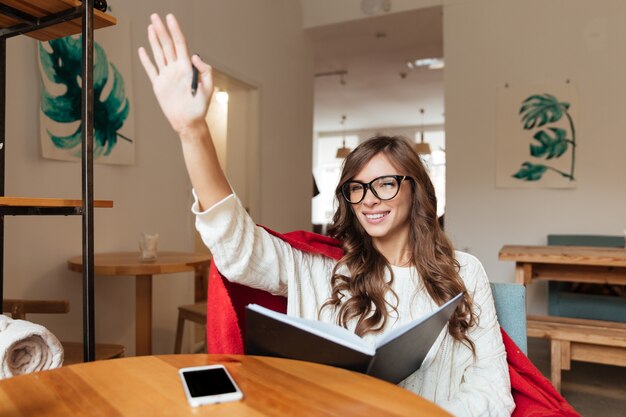 Portrait of a friendly woman in eyeglasses holding notepad