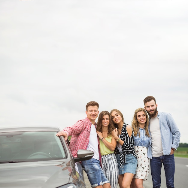 Foto gratuita ritratto di amici in piedi vicino all'automobile parcheggiata