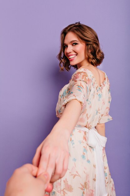 Portrait from back of laughing romantic girl holding photographer's hand