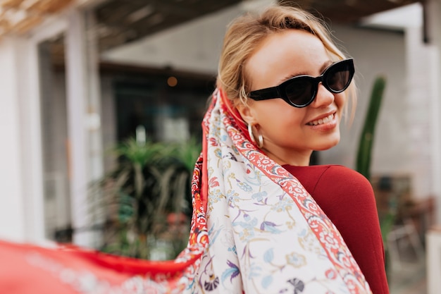 Portrait from back of smiling woman wearing black sunglasses and shawl in the head