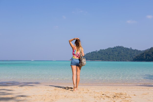 Portrait from back of tanned young woman looking on amazing blue sea and mountains view