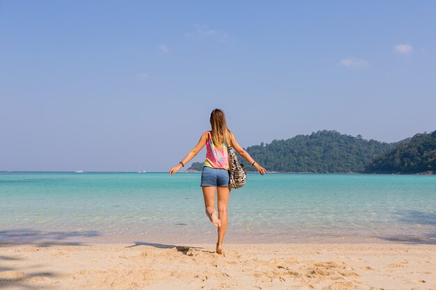 Portrait from back of tanned young woman looking on amazing blue sea and mountains view