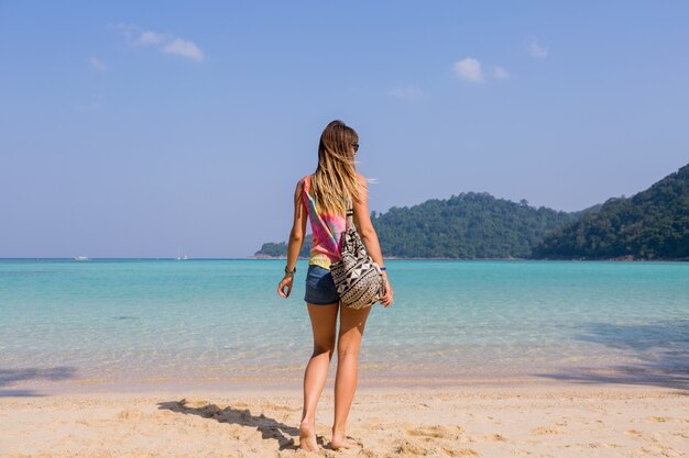 Portrait from back of tanned young woman looking on amazing blue sea and mountains view