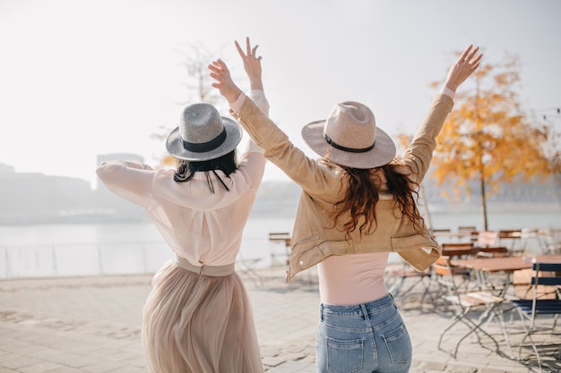 Portrait from back of two excited ladies expressing positive emotions enjoying river views