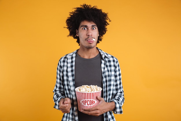 Портрет забавного афроамериканца, едящего попкорн