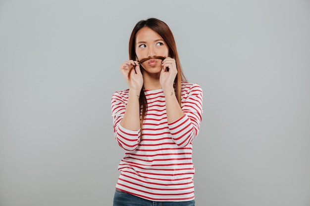 Free photo portrait of a funny asian woman playing with her hair