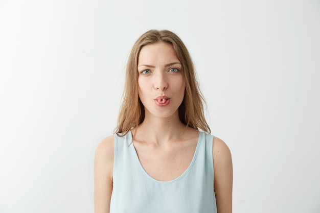 Portrait of funny cheerful young girl showing tongue .