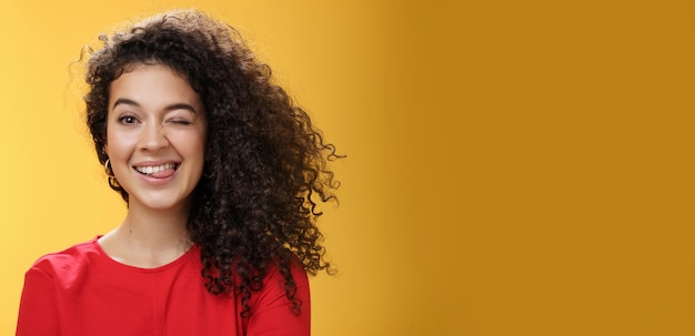 Free photo portrait of funny and cool sister with curly hair winking playfully having fun and foolind around sh