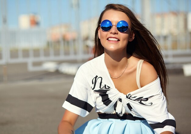 Portrait of funny crazy glamor stylish smiling beautiful young woman model in bright hipster summer casual clothes posing in the street on asphalt