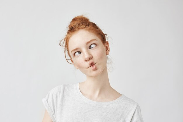 Portrait of funny cute ginger woman with freckles fooling.