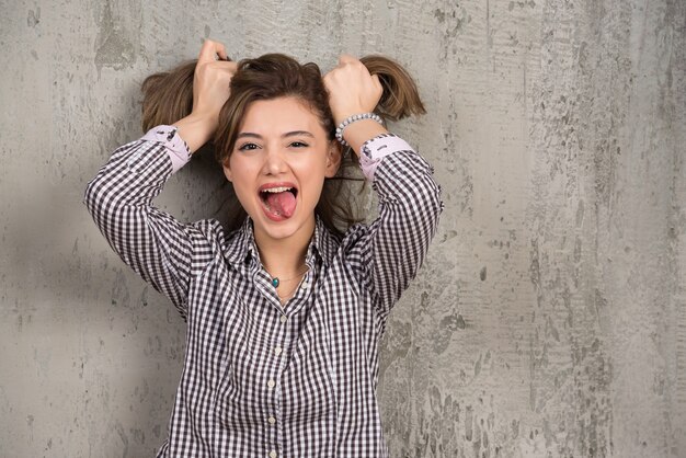 Portrait of funny girl doing two ponytails on head with her hands.