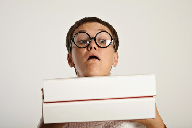 Portrait of funny girl student holding two heavy big folders with educational plan documents in front of her