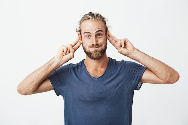 Foto gratuita ritratto dell'uomo bello divertente con la barba che fa i fronti sciocchi e che gesticola con le mani