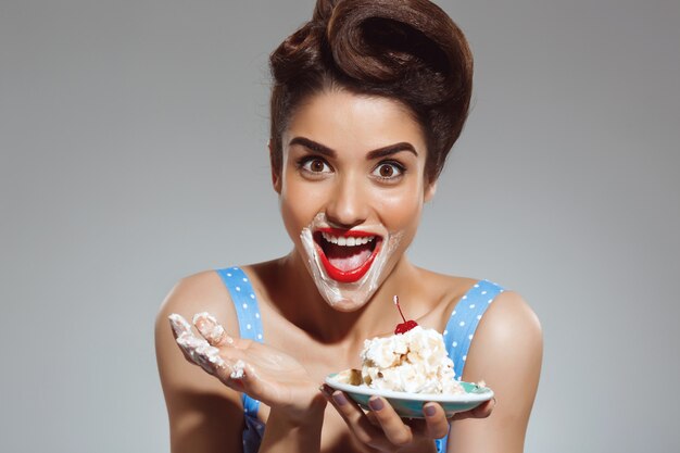 Portrait of funny pin-up woman eating cake