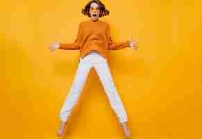 Free photo portrait of funny woman in white pants fooling around on yellow background