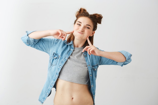 Portrait of funny young pretty girl with two buns making funny face fooling .