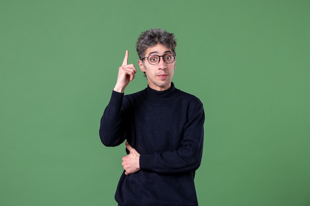 Free photo portrait of genius man dressed casually in studio shot has an idea green wall