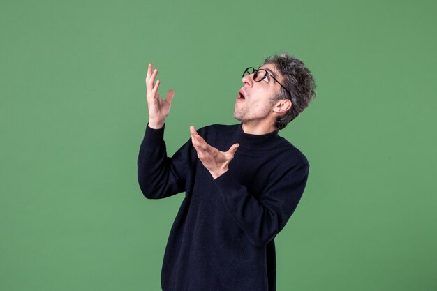 Portrait of genius man dressed casually in studio shot looking above on green wall