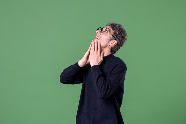 Portrait of genius man dressed casually in studio shot pleased green wall