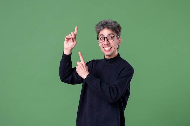 Free photo portrait of genius man dressed casually in studio shot pleased green wall